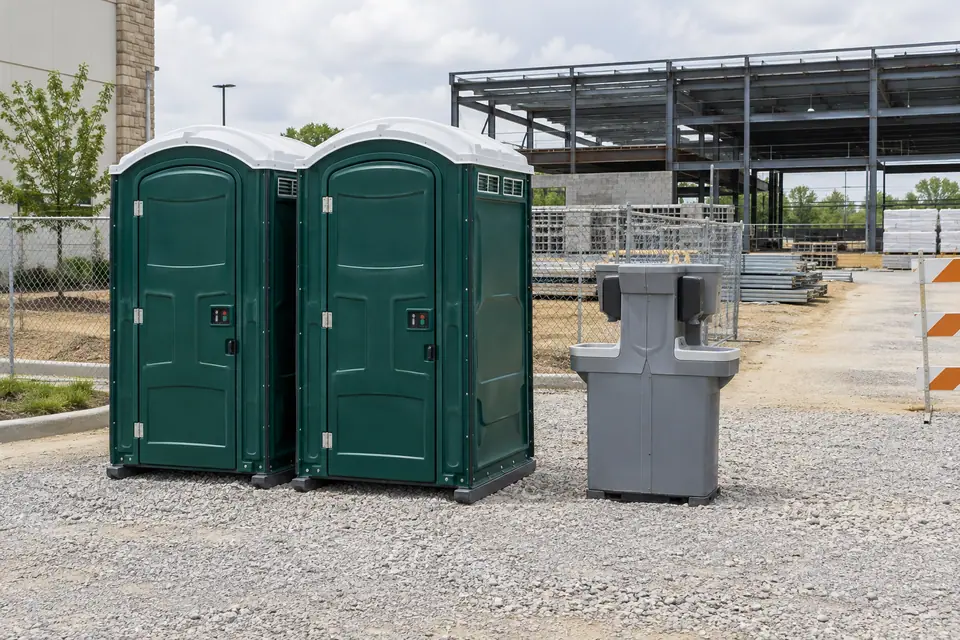 Portable toilets and handwashing station beside a commercial construction site